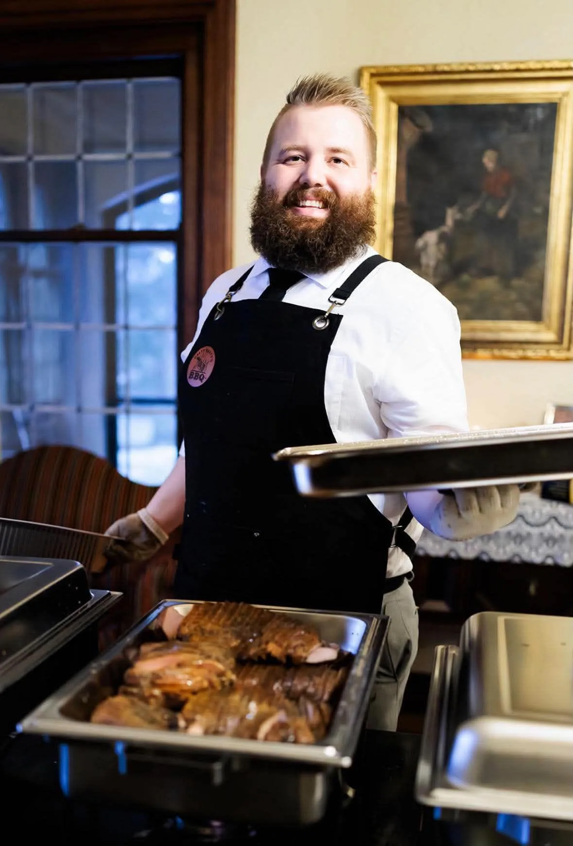 Dalton smiling behind a tray of barbecue at the buffet.