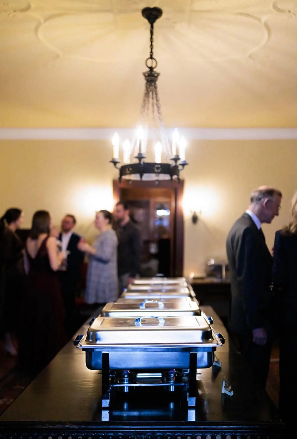Guests gathered beside a row of covered buffet dishes.